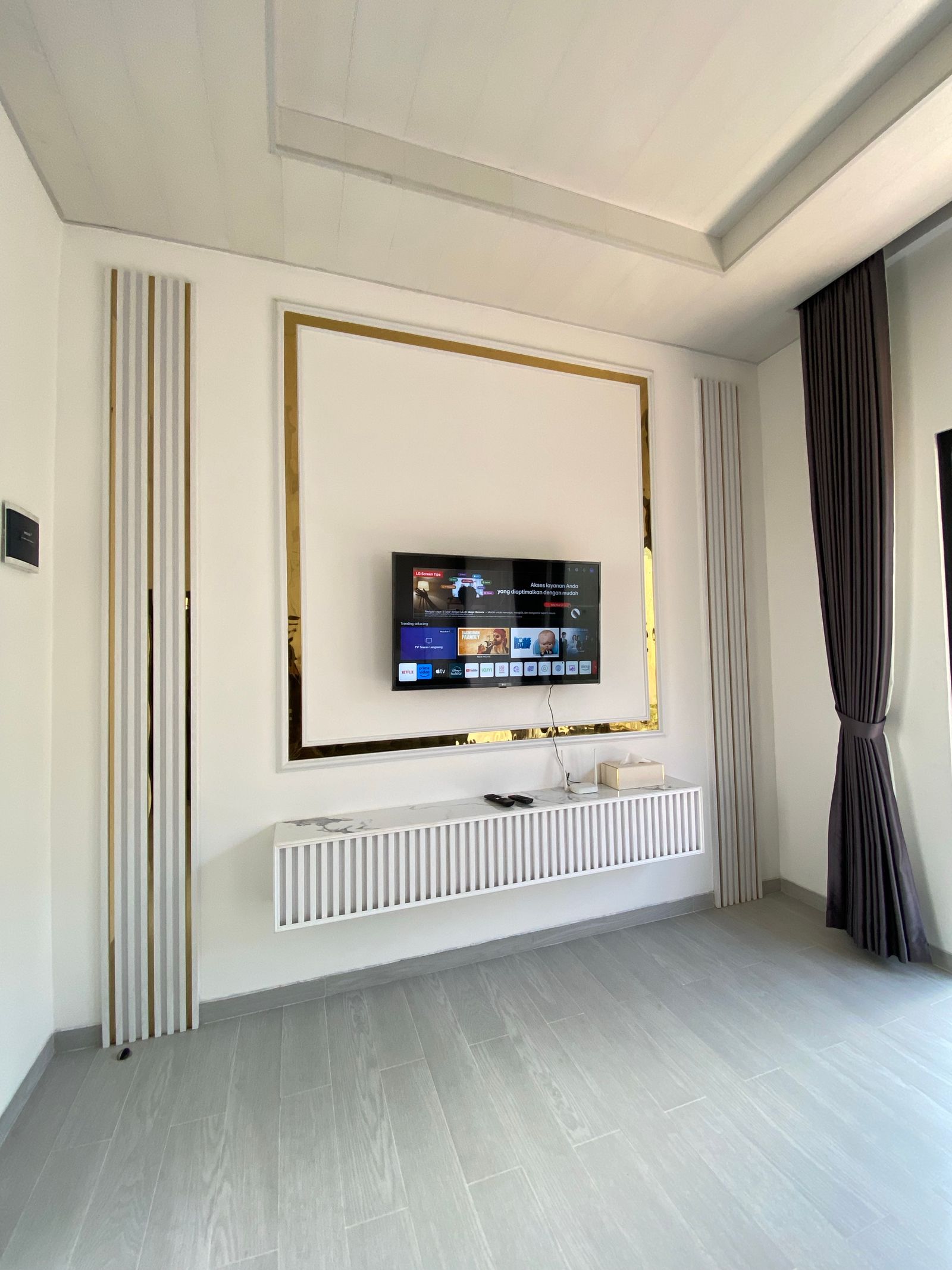 Minimalist living room with a wall-mounted TV in Mumbai City